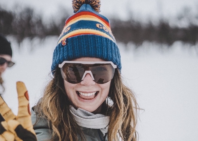 Glad kvinna med solglasögon på fjället.