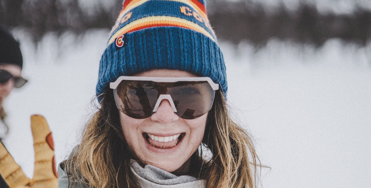 Glad kvinna med solglasögon på fjället.