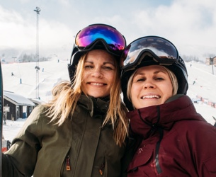 Två kvinnor som håller om varandra i skidbacken i Tänndalen.