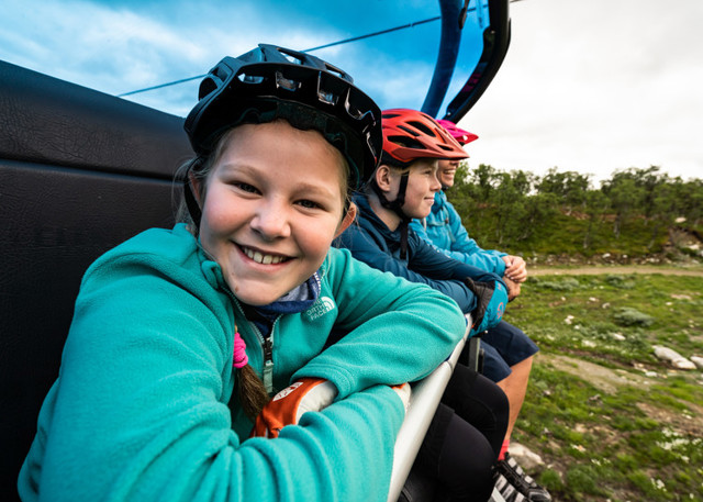 Happy children on the chairlift up the mountain in summer