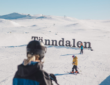 Två barn och en skidlärare vid Tänndalsskylten.