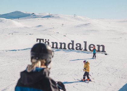 Två barn och en skidlärare vid Tänndalsskylten.