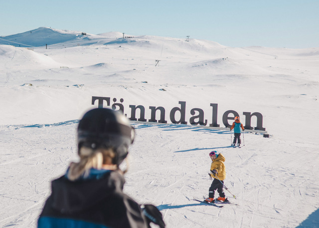 Två barn och en skidlärare vid Tänndalsskylten.
