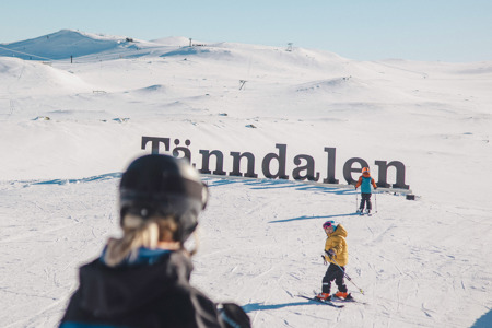 Två barn och en skidlärare vid Tänndalsskylten.